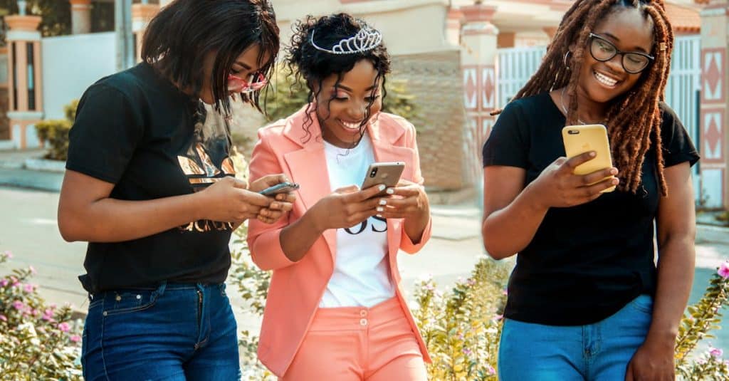 happy-ethnic-women-in-trendy-wear-text-messaging-on-cellphones-on-city-street