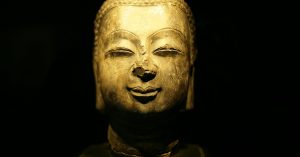 old-golden-sculpture-of-buddha-against-black-background