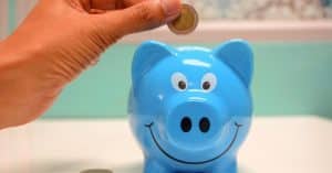 person-putting-coin-in-a-piggy-bank