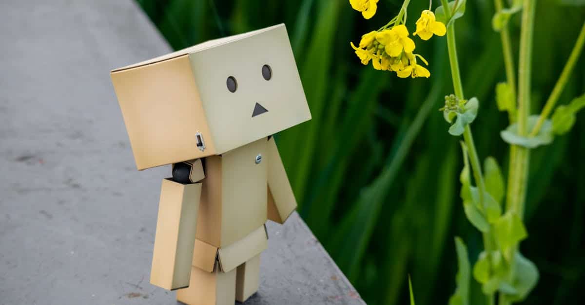 close-up-of-a-small-cardboard-figurine-standing-next-to-a-flower