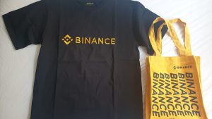Black Binance branded t-shirt and yellow Binance tote bag